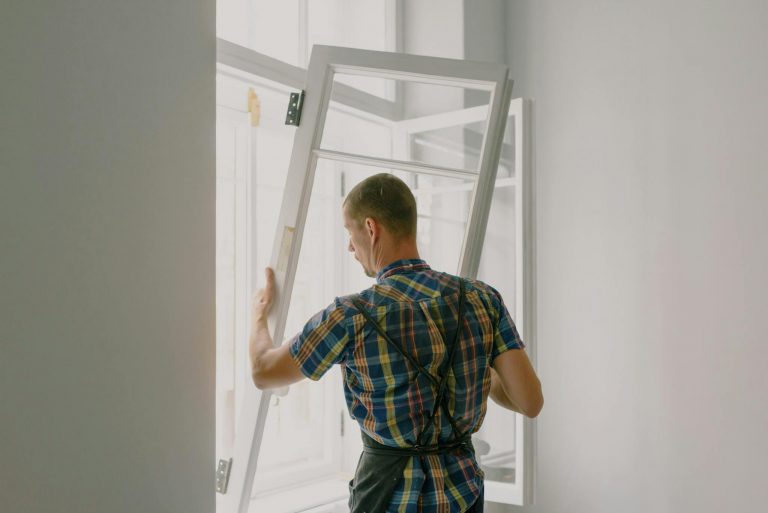 A professional installer fitting a modern window in a well-lit home interior.